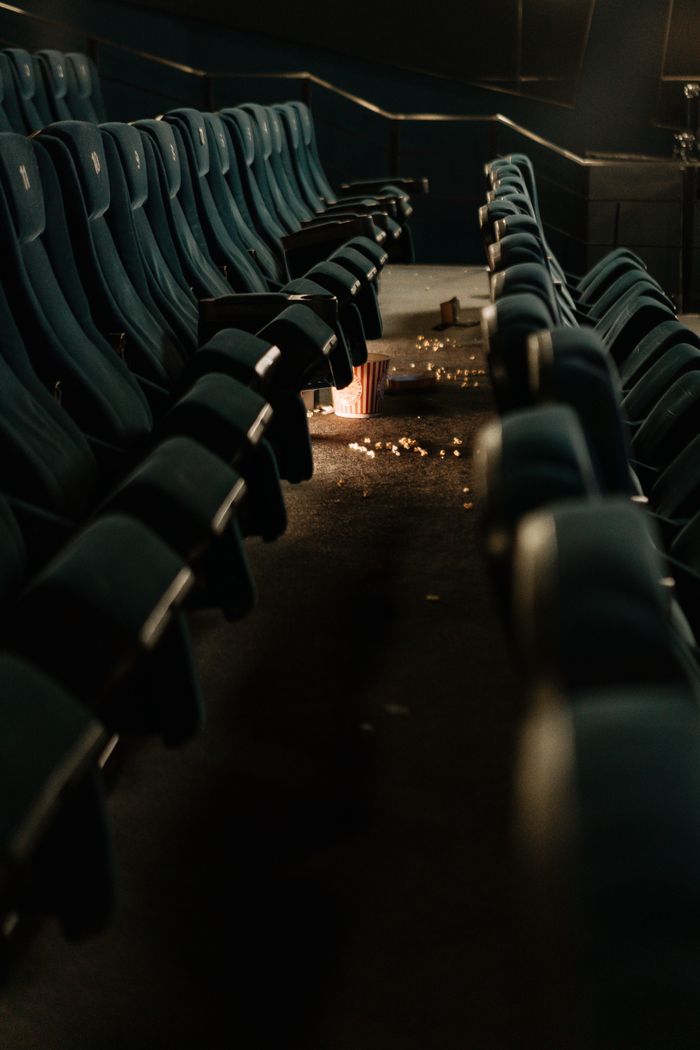 An empty cinema with scattered popcorn and dim lighting, capturing a post-movie ambiance.